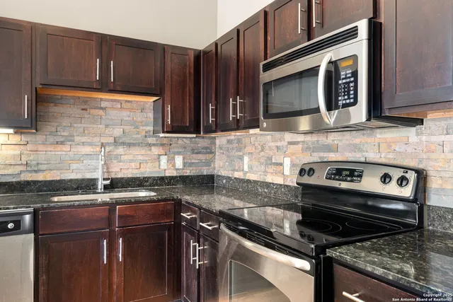 a kitchen with stainless steel appliances granite countertop a stove microwave and sink