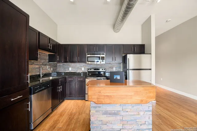 a kitchen with kitchen island granite countertop wooden cabinets a stove top oven a sink and dishwasher