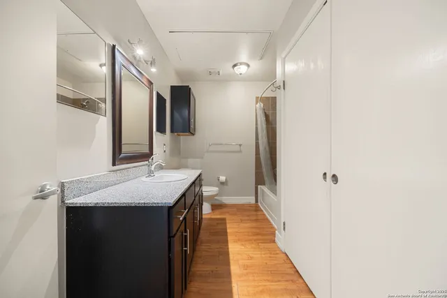 a en suite bathroom with a granite countertop sink and a mirror
