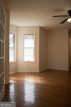 a view of an empty room with wooden floor and a window