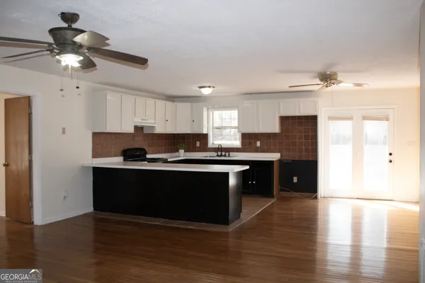 a kitchen with stainless steel appliances granite countertop a sink a stove a refrigerator and island with wooden floor