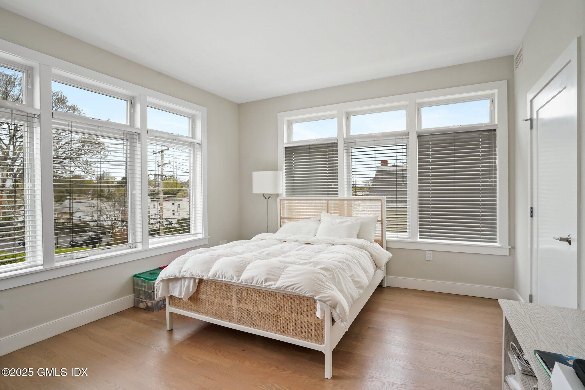 56 Old Field Point Road, Unit 1 Greenwich, CT 06830 - Photo 15 of 20 a bedroom with a bed and a large window