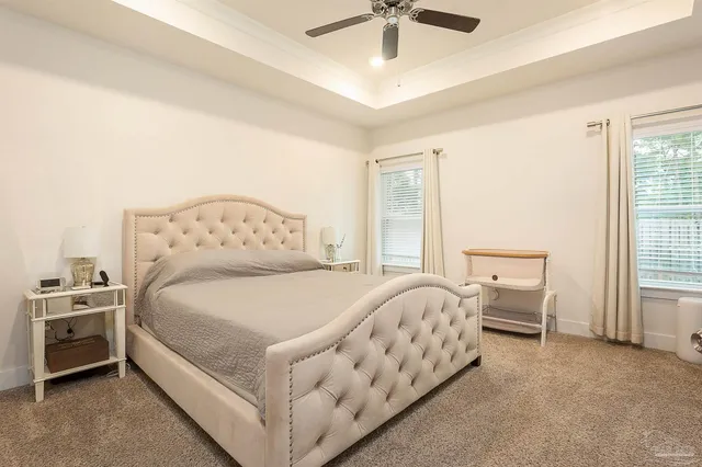 a large bed sitting in a bedroom next to a window and a chandelier