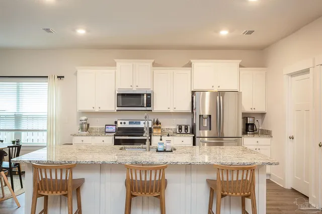 a kitchen with stainless steel appliances granite countertop a sink a stove a microwave a dining table and chairs