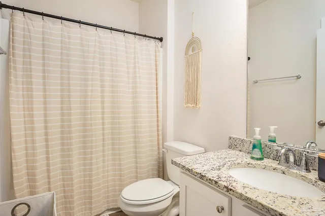 a bathroom with a granite countertop bathtub sink vanity mirror and toilet