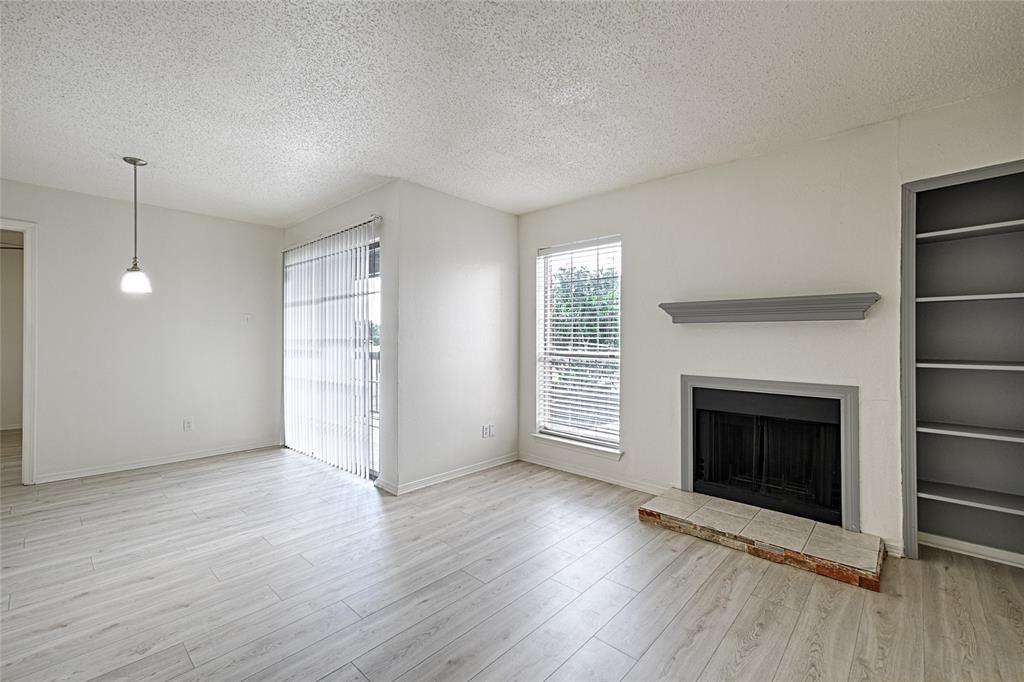 an empty room with wooden floor fireplace and windows