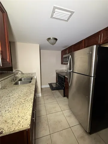a kitchen with granite countertop a refrigerator and a sink