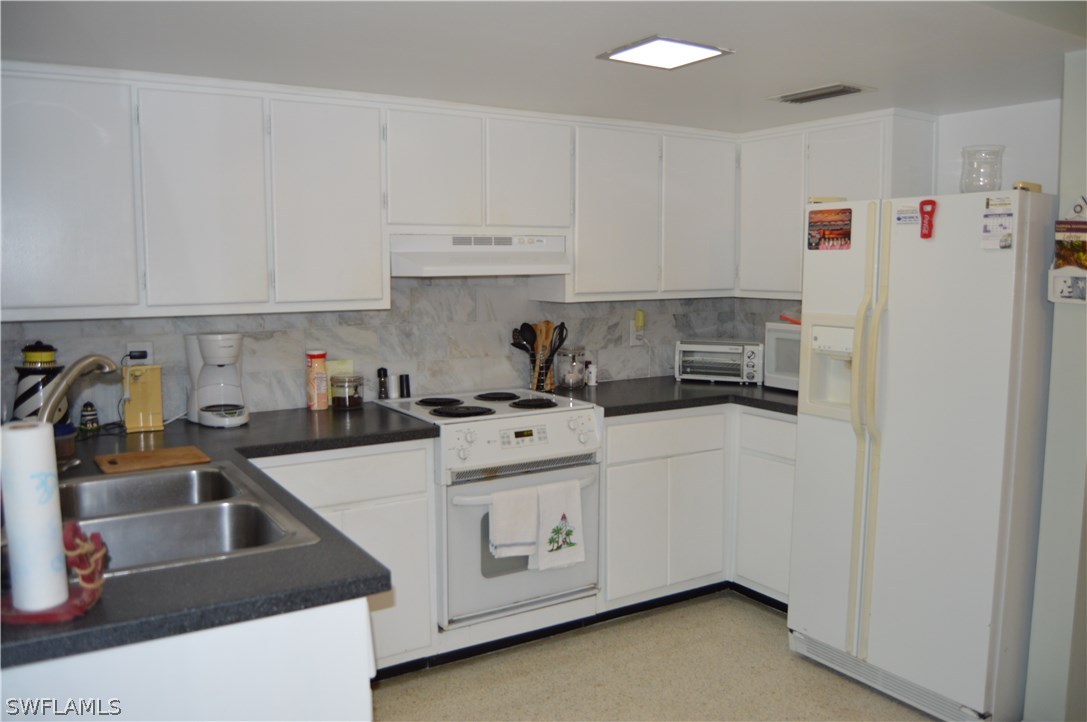 2822 Bruce Street Cape Coral, FL 33993 - Photo 14 of 20 a kitchen with white cabinets and white appliances