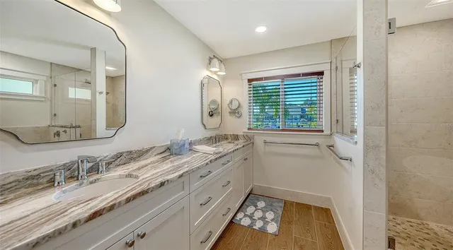 a bathroom with a granite countertop bathtub sink vanity mirror and toilet