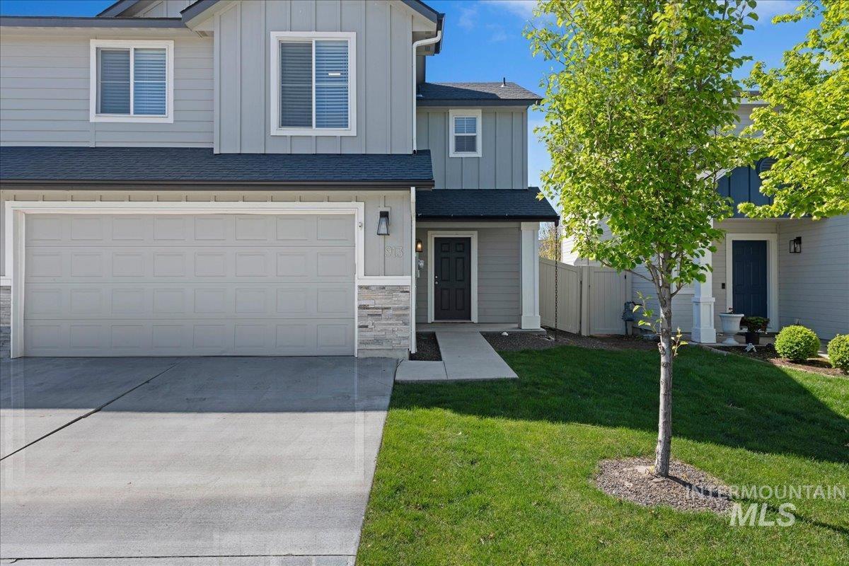Contemporary two-story exterior featuring a two-car garage, light gray siding, and stone accents