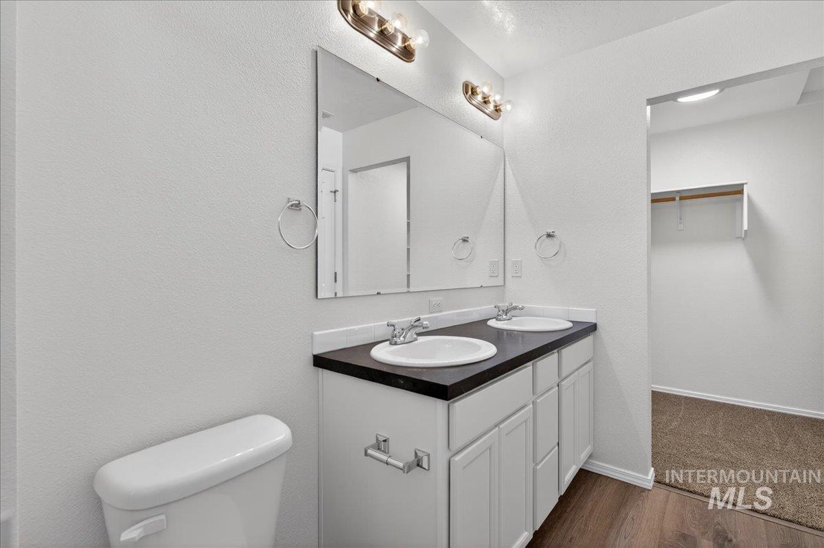 913 West Apple Pine Street Meridian, ID 83646 - Photo 21 of 32 Dual vanity with white cabinetry and dark countertop, featuring two integrated sinks and wall-mounted light fixtures
