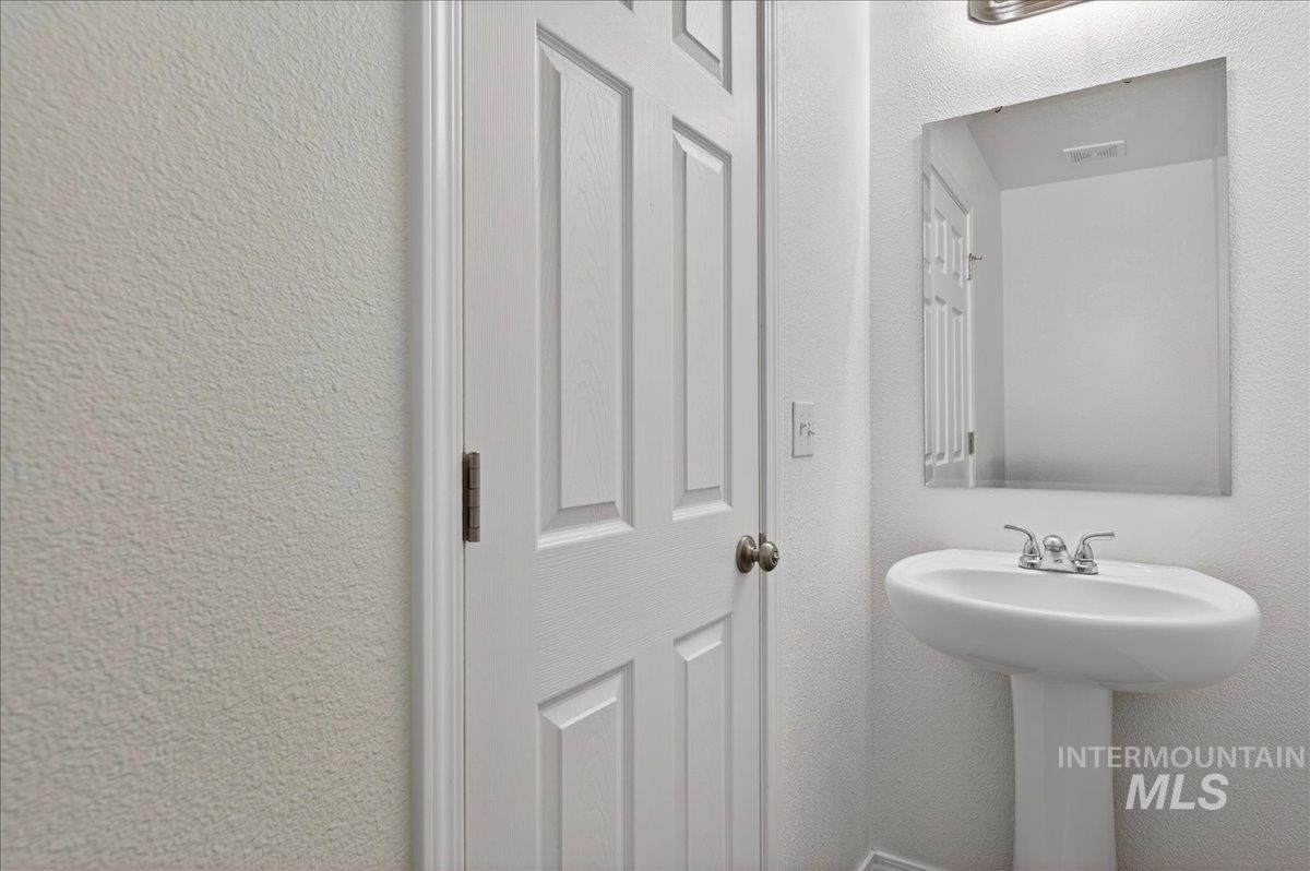 913 West Apple Pine Street Meridian, ID 83646 - Photo 23 of 32 Pedestal sink with chrome faucet, complemented by a rectangular frameless mirror and overhead vanity lighting