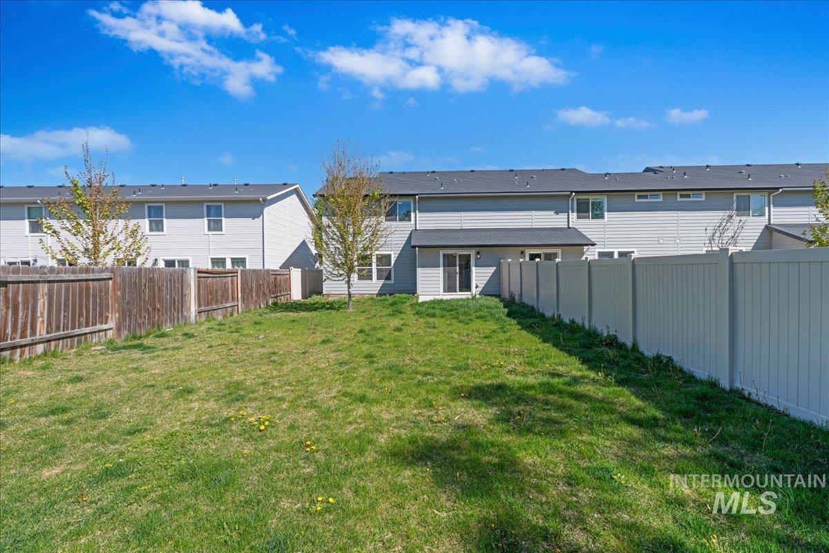 913 West Apple Pine Street Meridian, ID 83646 - Photo 28 of 32 Expansive backyard featuring a lush lawn, a white privacy fence, and a wood-paneled fence, with a sliding glass door providing access to the residence