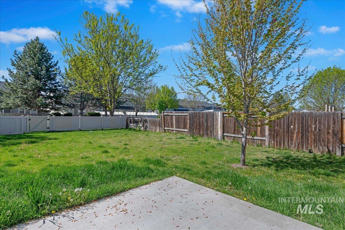 913 West Apple Pine Street Meridian, ID 83646 - Photo 29 of 32 Expansive backyard featuring a concrete patio, mature trees, partial wood fencing, and partial white vinyl fencing