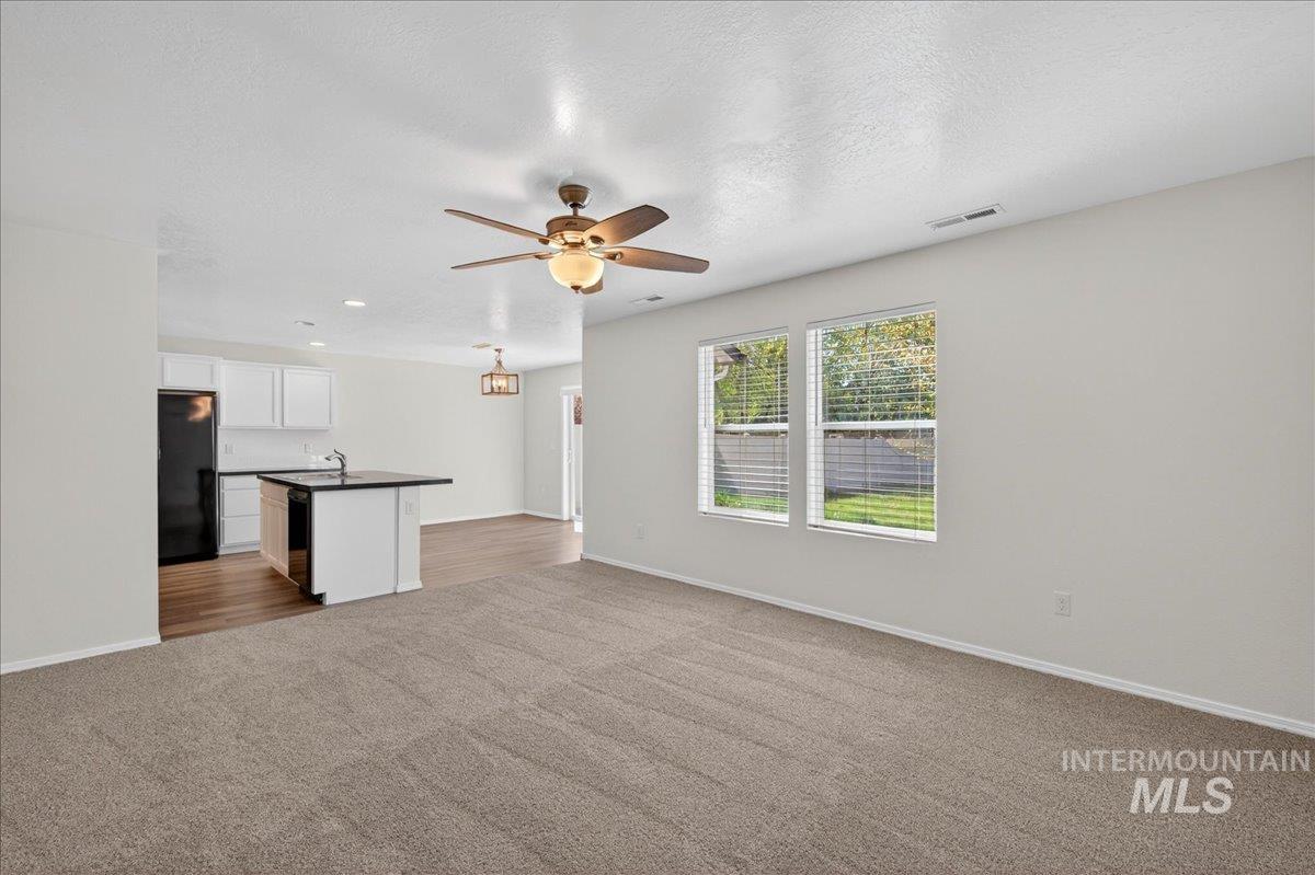 913 West Apple Pine Street Meridian, ID 83646 - Photo 4 of 32 Open concept living area featuring carpet flooring, a ceiling fan with integrated lighting, and two windows with blinds