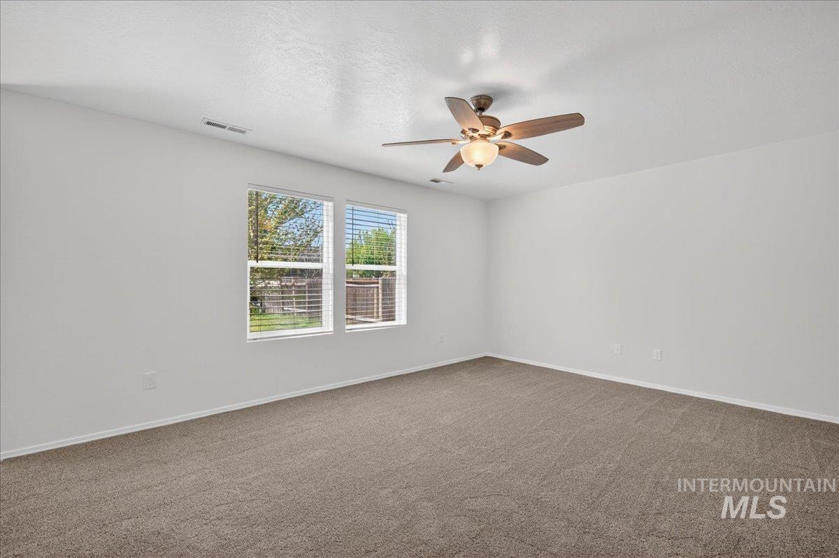 913 West Apple Pine Street Meridian, ID 83646 - Photo 6 of 32 Bright interior space featuring neutral wall tones, two large windows with blinds, a ceiling fan with integrated lighting, and plush carpet flooring