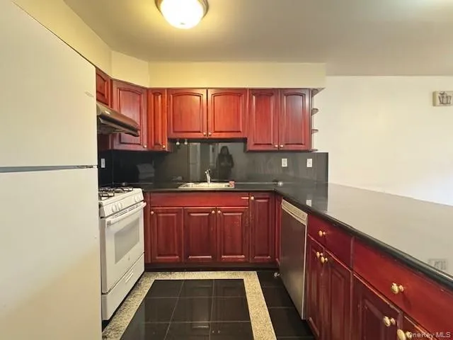 a kitchen with stainless steel appliances granite countertop a refrigerator a stove and wooden cabinets