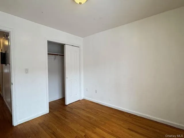 a view of an empty room with wooden floor and closet
