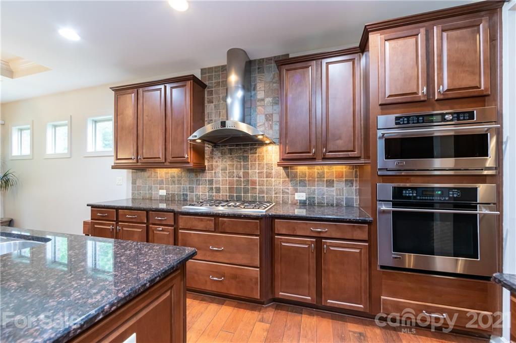 2721 Twinberry Lane Waxhaw, NC 28173 - Photo 3 of 29 a kitchen with kitchen island granite countertop a stove kitchen island granite countertop wooden cabinets and a refrigerator