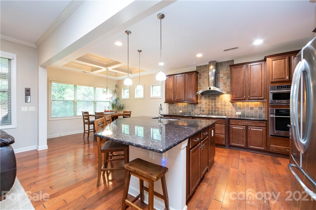 2721 Twinberry Lane Waxhaw, NC 28173 - Photo 4 of 29 a kitchen with stainless steel appliances granite countertop a stove top oven a sink dishwasher a dining table and chairs with wooden floor