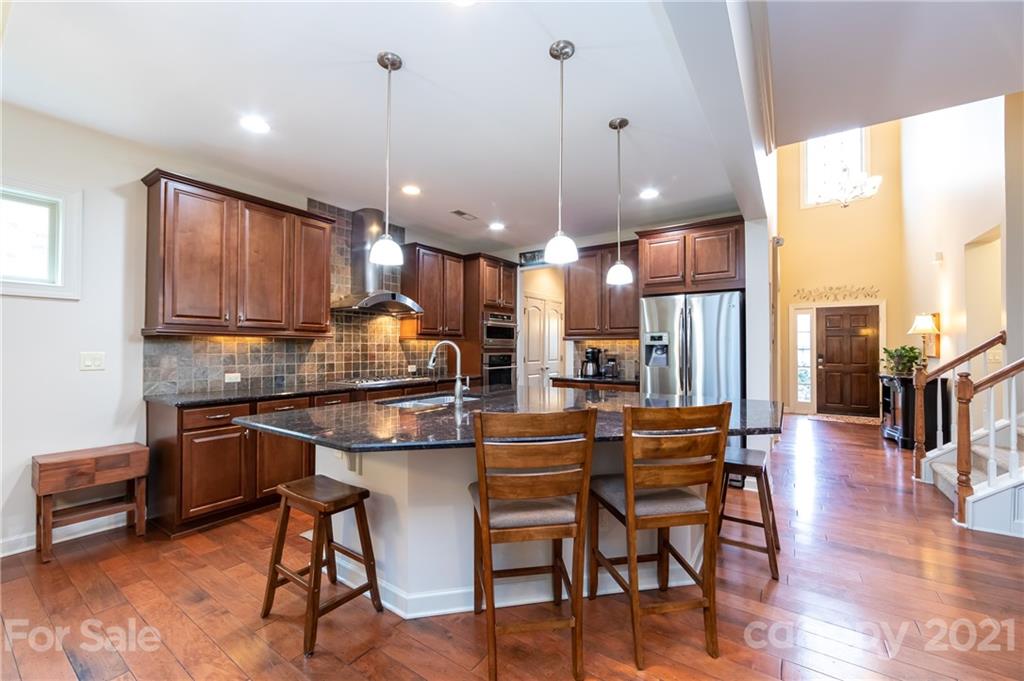 2721 Twinberry Lane Waxhaw, NC 28173 - Photo 5 of 29 a kitchen with stainless steel appliances a dining table chairs stove and white cabinets