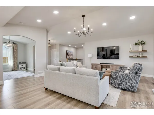 a living room with furniture kitchen view and a wooden floor