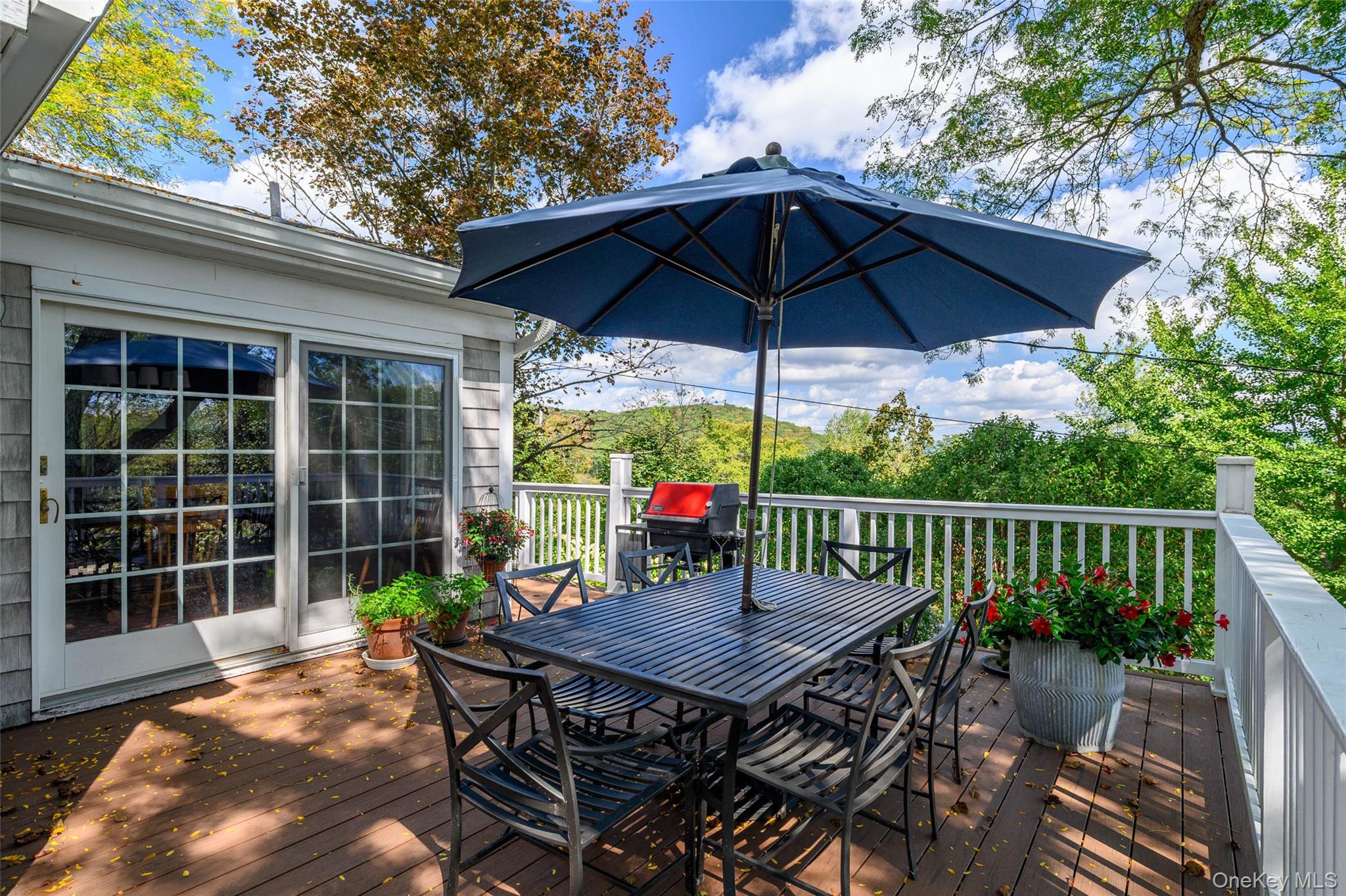475 Mooney Hill Road Patterson, NY 12563 - Photo 27 of 47 a view of a deck that has a table and chairs under an umbrella