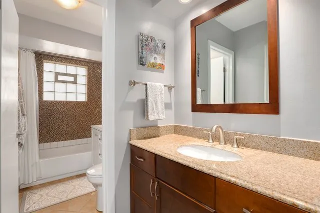 a bathroom with a granite countertop sink a toilet and shower