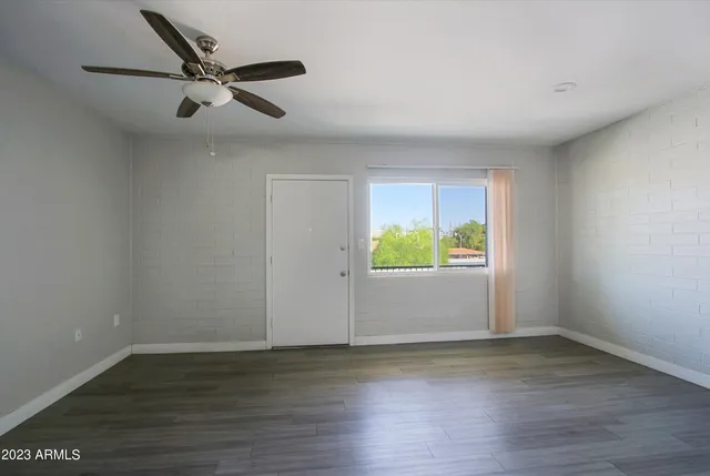 a view of an empty room with wooden floor and a window