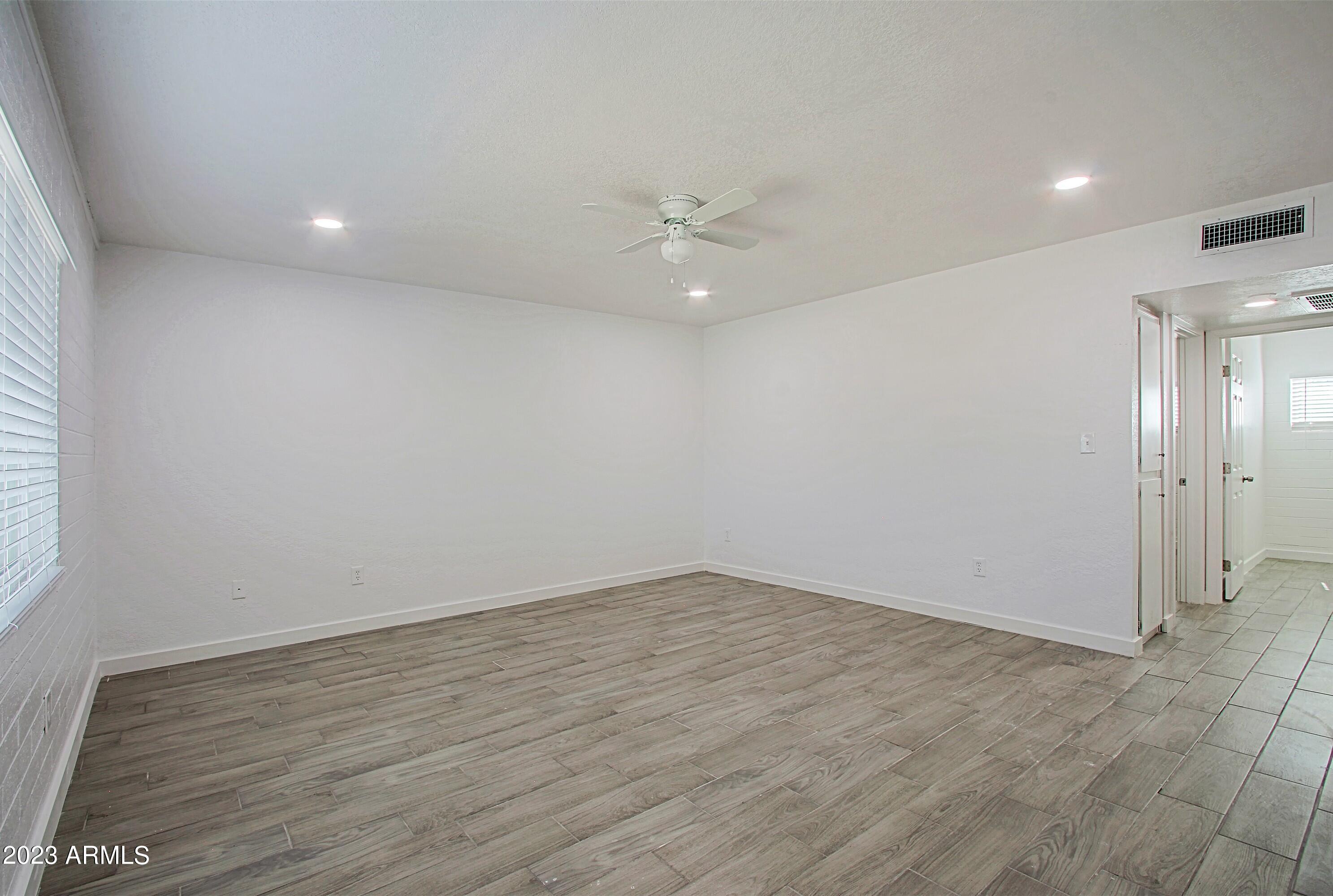 3219 East Earll Drive, Unit 9 Phoenix, AZ 85018 - Photo 6 of 12 an empty room with a window and a ceiling fan