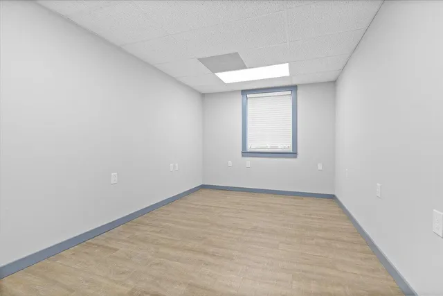 a view of an empty room with window and wooden floor