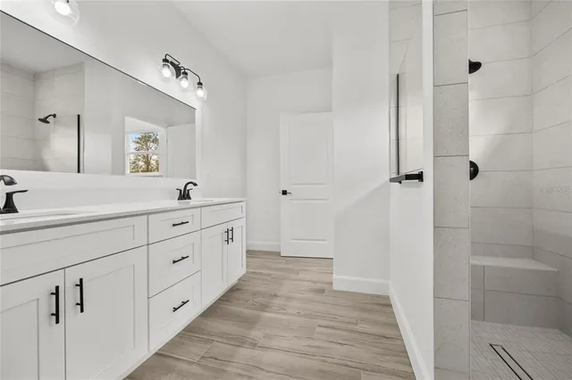 a spacious bathroom with a double vanity sink a mirror and shower