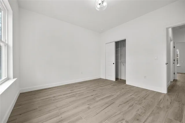 an empty room with wooden floor and windows