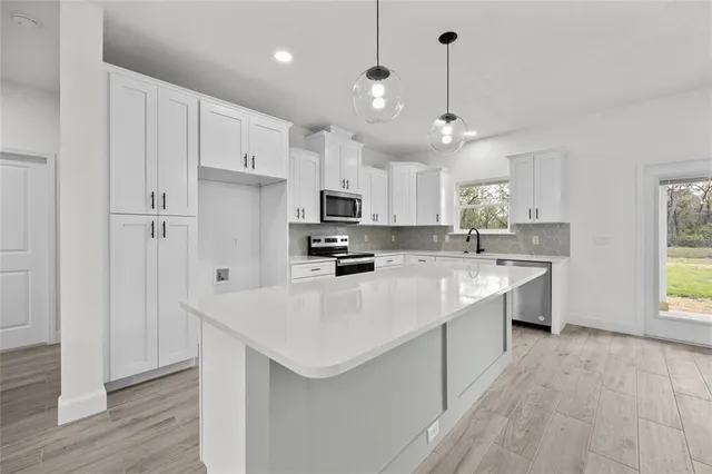 a large white kitchen with lots of counter space a sink appliances and cabinets