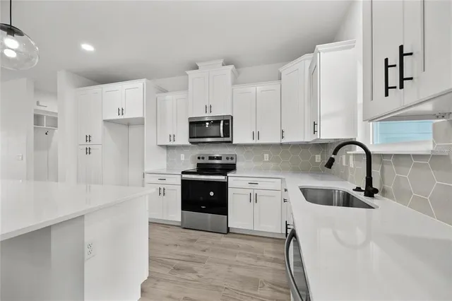 a kitchen with stainless steel appliances granite countertop white cabinets a sink a stove a refrigerator and dishwasher