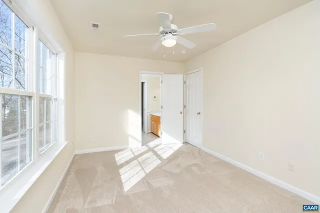 an empty room with windows and ceiling fan
