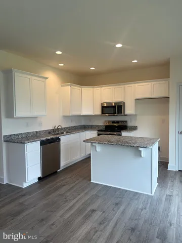 a kitchen with granite countertop wooden floors stainless steel appliances and sink