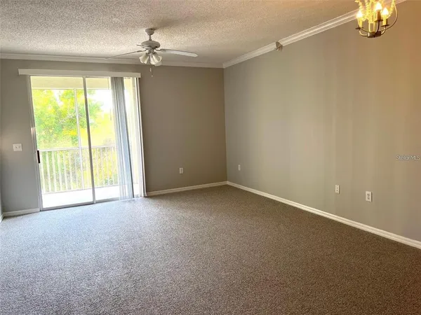 an empty room with a chandelier fan and windows