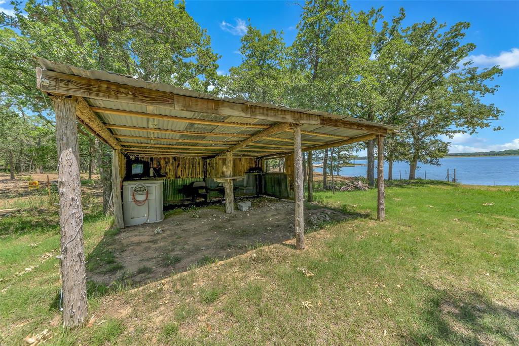 566 Selma Park Road Bowie, TX 76230 - Photo 33 of 40 Rustic covered outdoor structure featuring natural wood posts and a corrugated metal roof