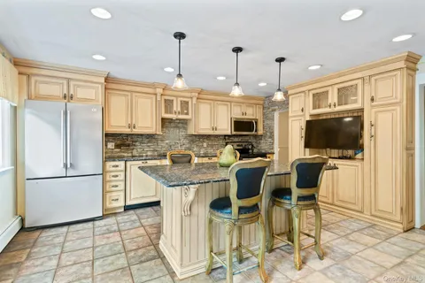 a kitchen with stainless steel appliances granite countertop a stove a refrigerator a kitchen island a dining table and chairs with wooden floor