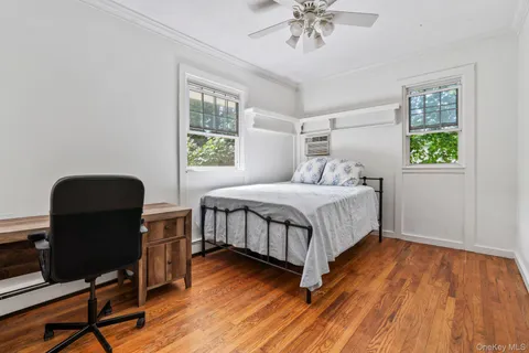 a bedroom with a bed a dresser and wooden floor