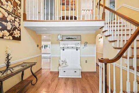 a view of a hallway with wooden floor stairs and a kitchen view