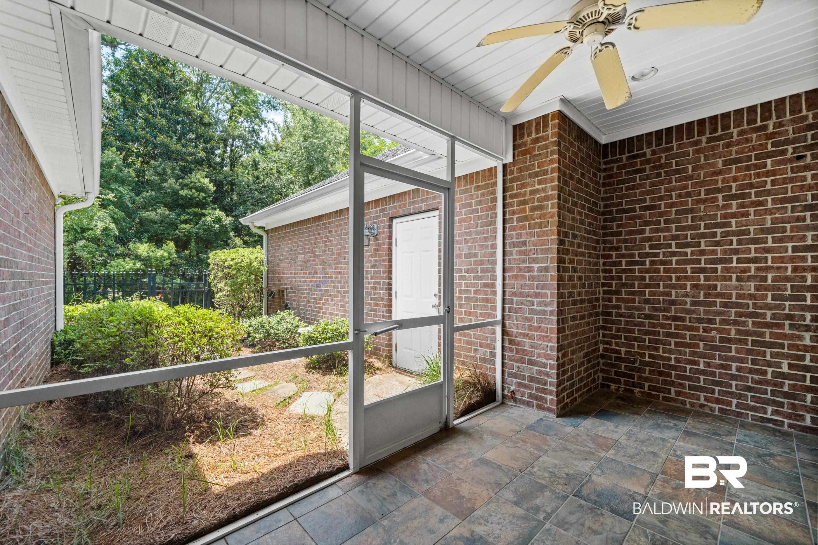 303 Savannah Circle Foley, AL 36535 - Photo 26 of 34 Screened porch featuring brick walls, slate-look tile flooring, and a ceiling fan