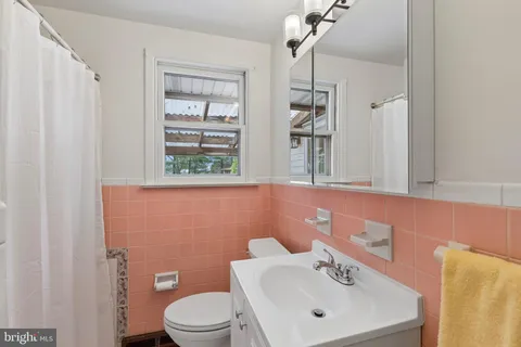 a bathroom with a toilet a sink a mirror and a window