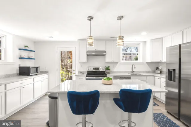 a kitchen with stainless steel appliances kitchen island granite countertop a stove and white cabinets