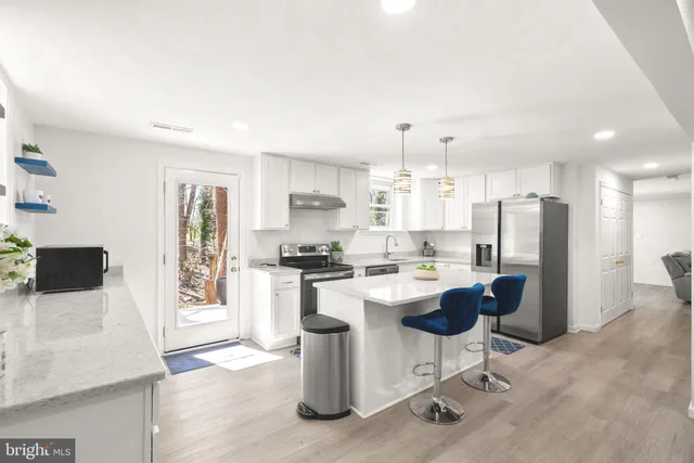 a kitchen with a refrigerator a stove a sink a dining table and chairs