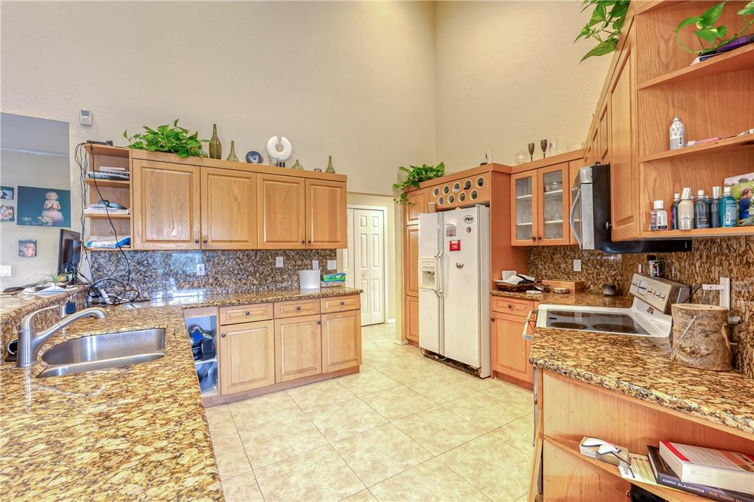 22372 Collington Drive Boca Raton, FL 33428 - Photo 15 of 22 a kitchen with stainless steel appliances granite countertop a sink stove and refrigerator