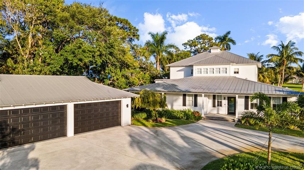 3404 Southeast Inlet Harbor Trail Stuart, FL 34996 - Photo 5 of 32 a view of a white house with a yard and table and chairs under an umbrella