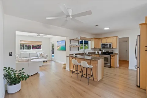 a kitchen with a sink cabinets stainless steel appliances and a dining table