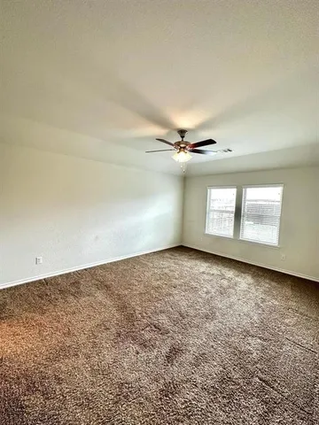an empty room with windows and ceiling fan view